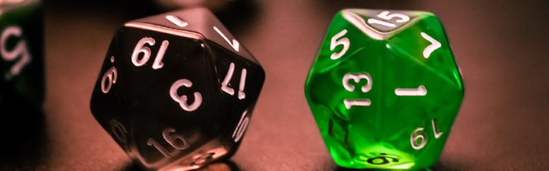 Two twenty-sided dice side-by-side. One die, black, is showing a 1 and the other, green, is showing a 20